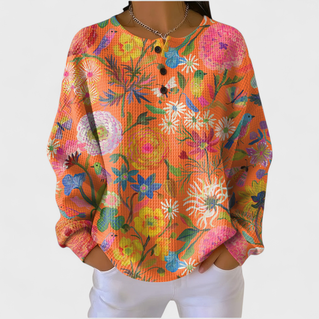 Gerhild Pullover mit Blüten auf Koralle – warmes Korallenrot mit gemalten Blüten in Pink, Blau und Gelb über die ganze Fläche – Stefan Berlin
